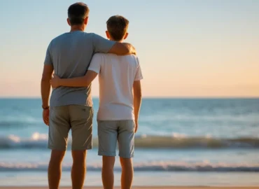 Pai e filho abraçados na praia, simbolizando a dúvida sobre a continuidade da pensão alimentícia após os 18 anos para custear os estudos.