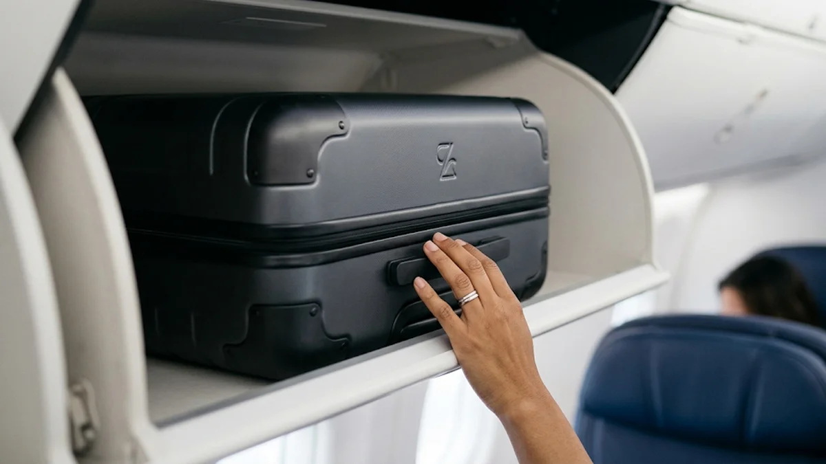 Detalhe de mala de mão em compartimento superior de avião, simbolizando direitos do passageiro.